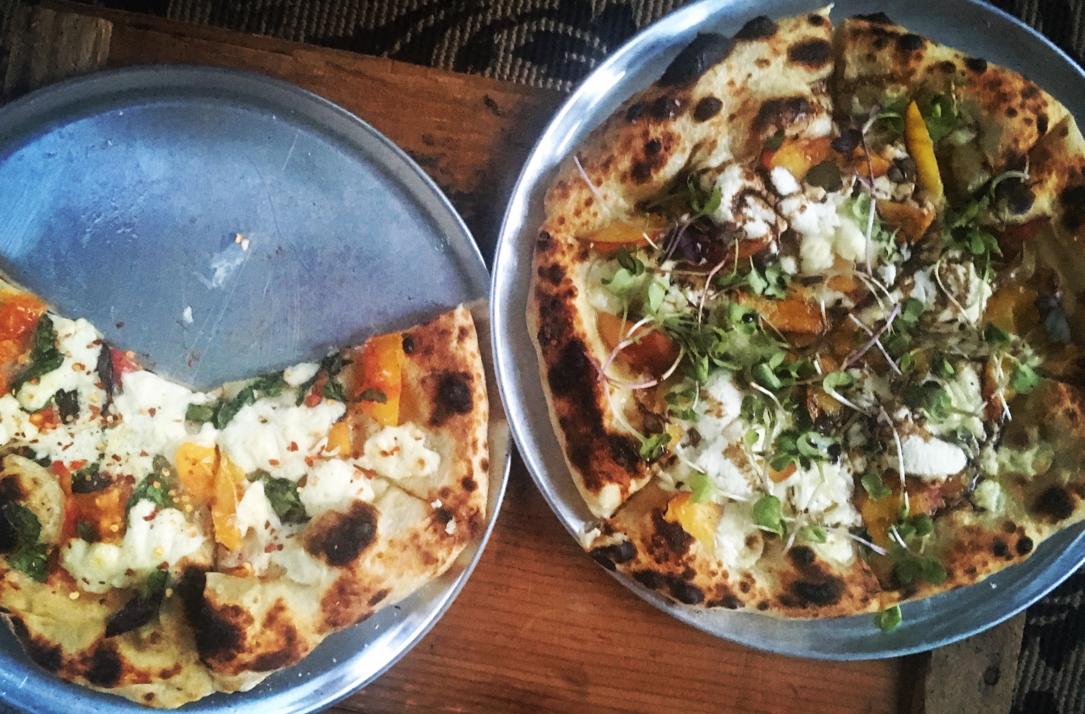 two vegan pizzas on pizza trays